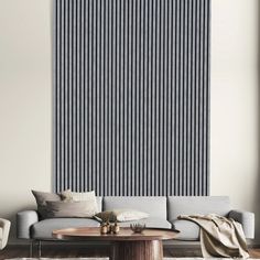 a living room with a couch, coffee table and large vertical striped wall hanging on the wall