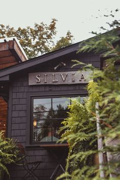 the outside of a restaurant with tables and chairs in front of it's windows