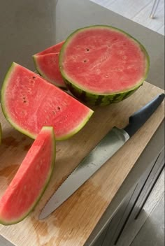 two slices of watermelon on a cutting board with a knife