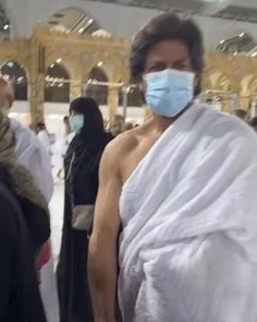 a woman wearing a face mask while standing next to a man in a white robe