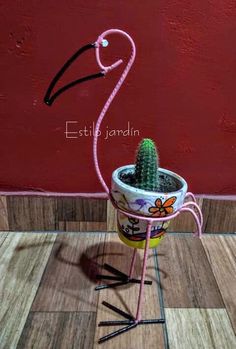 a pink flamingo plant sitting on top of a wooden floor next to a red wall