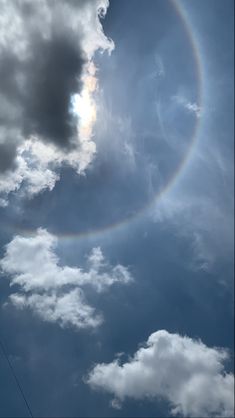 a rainbow appears to be in the sky with clouds and power lines behind it, as seen from below