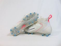 a pair of white shoes with blue and pink spikes on the soles, against a white background