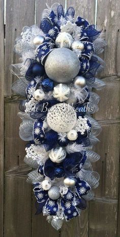 a blue and white christmas wreath hanging on a wooden fence