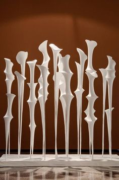 a group of tall white sculptures sitting on top of a marble floor next to a brown wall