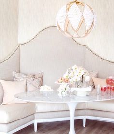 a white table with flowers on it in front of a couch and chandelier