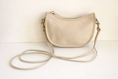 "Coach double strap Swinger bag in bone leather. This vintage Coach bag is high quality featuring a spacious interior, zipper closure, removable shoulder strap, and small interior compartment. The Coach Swinger has been cleaned and conditioned.  The Coach Swinger is in good condition with imperfections. Imperfections include heavy pen markings on the interior and some ink bleeding onto the exterior bottom corner. Additional imperfections can been seen on the light colored leather. Please review Vintage Cream Leather Shoulder Bag, Coach Swinger, Vintage Coach Bag, Contemporary Costumes, Vintage Coach Bags, Painted Pony, Jewelry Chest, Basic Jewelry, Horse Figurine