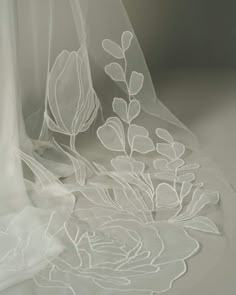 a white veil with flowers and leaves on it