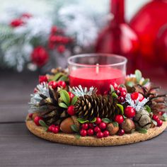 a candle is sitting on top of a cookie with holly and pine cones around it