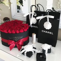 two black boxes with red roses in them and one has a bottle of chanel