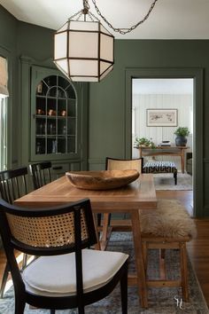 a dining room table with chairs and a bowl on top of it in front of green walls