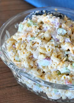 a bowl filled with macaroni salad on top of a wooden table