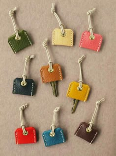 six small leather luggage tags with metal clips attached to each one's sides, all in different colors