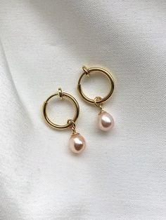 Dainty pearl teardrop earrings featuring a pair of tiny fresh water pearls in natural peachy pink color. Dangling from a small brass clip-on hoops in 18k gold plating. These earrings are timeless and give a modern vibe.  The earrings can be customised for pierced ears with 18k gold plated brass hoops please select Style at basket. Total length about 2.3cm.  Details: Fresh water keshi pearls  14k gold-filled metal wires 18k gold plated brass clip-on hoops/ 18k gold plated brass piercing hoops Follow us on Instagram @lazypeachjewellery for updates and promotions! Care for your pearls: To preserve your pearls' lustre, avoid letting them come into contact with cosmetics, hair spray, or perfume. Daily care for pearls, gently wipe your pearl jewelry with soft cloth to clean off the grime.  Pleas Pearl Teardrop Earrings, Pink Pearl Earrings, Pearl Dangle Earrings, Fresh Water Pearls, Hair Spray, Keshi Pearls, Water Pearls, Pearl Earrings Dangle, Pink Earrings