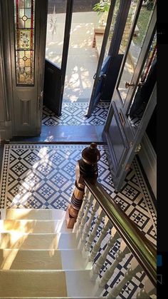 the stairs lead up to an entryway with stained glass doors and decorative flooring