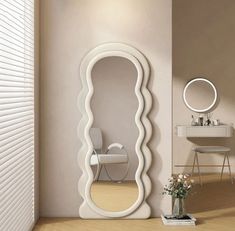 a large white mirror sitting on the side of a wall next to a table and chair