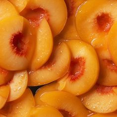 sliced peaches with water droplets on them are piled up together in a pile and ready to be eaten