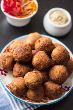 some food is sitting on a plate with dipping sauces in the bowl behind it