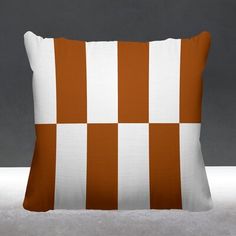 an orange and white checkered pillow sitting on top of a gray floor next to a black wall