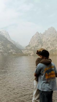 two people standing on the shore of a lake