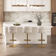 three white stools sit in front of an island with marble countertops and cabinets