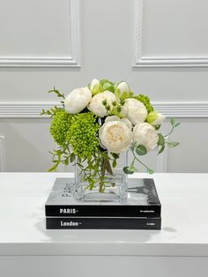 a vase filled with white flowers sitting on top of a book