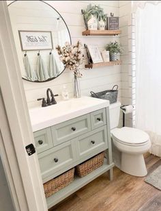 a white toilet sitting next to a sink in a bathroom under a mirror and shelves