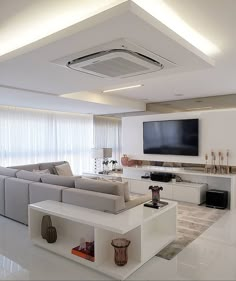 a living room with white furniture and a flat screen tv mounted above the entertainment center