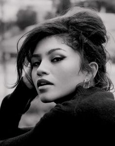 a black and white photo of a woman with her hand on her head looking off to the side