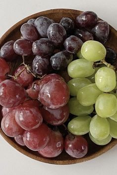 a wooden bowl filled with lots of grapes