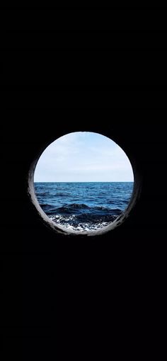 an ocean view through a hole in the wall