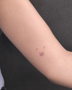 a small pig tattoo on the left forearm and arm, with pink ink in it's eyes