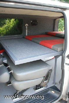 the back end of a van with two seats and a table on it's side