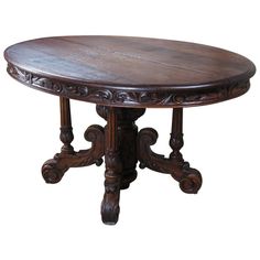 an oval wooden table with ornate carvings on the top and bottom, in dark wood