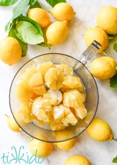 a glass bowl filled with sliced lemons on top of a marble counter next to green leaves