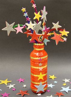 an orange vase filled with stars on top of a table