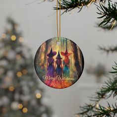 a christmas ornament with three witches hanging from it's side in front of a christmas tree