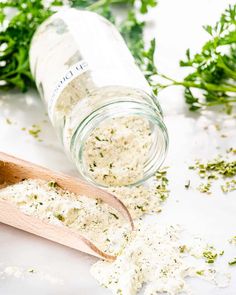 a wooden spoon filled with herbs next to a jar full of seasoning and sprinkles