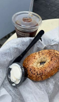 a bagel and cup of coffee sitting on top of a white tablecloth covered table