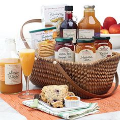 a basket filled with jams, cookies and orange juice