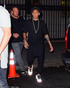 a man in black shirt and hat standing next to an orange cone with his foot on the ground