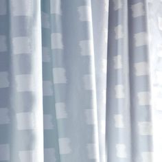 a cat sitting on top of a window sill in front of a white curtain