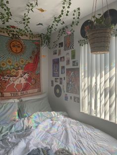 an unmade bed in a room with posters on the wall and plants hanging from the ceiling