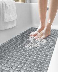 a person washing their feet in a bathtub with soap on the floor and water coming out of it