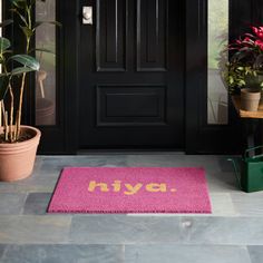 a pink door mat with the word nive on it next to potted plants