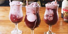 three glasses filled with ice cream sitting on top of a wooden table