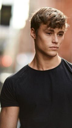 a young man is standing in the street with his hand on his hip and looking at the camera