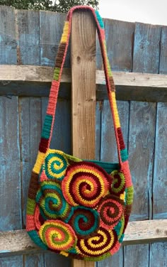 a crocheted bag hanging on a wooden fence