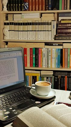 a laptop computer sitting on top of a desk next to a book shelf filled with books