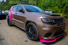 a brown and pink jeep parked on the side of a road next to other cars